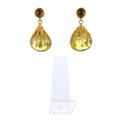 une paire de boucles d'oreilles ornées d'un coquillage doré sur fond blanc