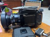 a black camera sitting on top of a table next to a cell phone