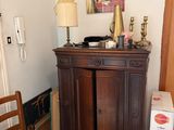 a wooden cabinet in the corner of a room next to a chair