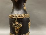 a black and gold vase sitting on a stand