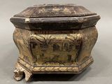 an old metal box with a painting on it sitting on a table