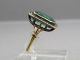 a close up of a ring with a green stone on it