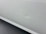 a close up of a white car with scratches on the side of it