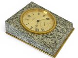 une horloge en marbre avec des chiffres romains sur le dessus, posée sur une surface blanche