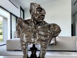 une statue représentant un homme assis sur une table dans un salon