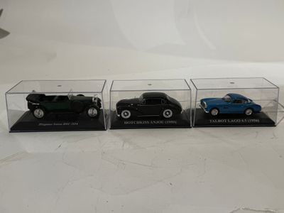trois petites voitures dans une vitrine posée sur une table