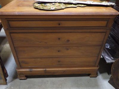 a wooden chest of drawers in a room with many other items