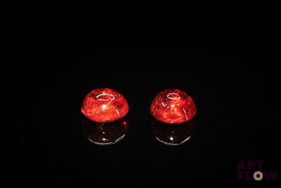 une paire de bougeoirs en verre rouge posés sur une surface noire