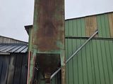 a green building with a rusted metal door and a green building in the background