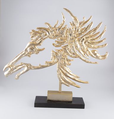 une sculpture représentant une tête de cheval en or, posée sur un socle en marbre noir