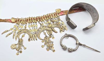 un collier en argent et en or et une paire de ciseaux posés sur une surface blanche