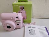 a pink camera sitting on a table next to a green box
