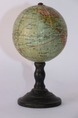 un petit globe vert posé sur un socle noir, sur fond blanc