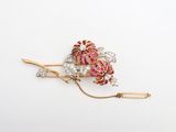 un gros plan sur une broche rose et dorée ornée de perles