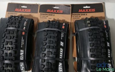 Trois pneus de VTT Maxxis sont exposés dans une boîte
