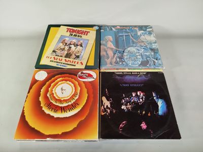 quatre albums de styles musicaux variés sont posés sur une surface blanche