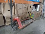 a red hand truck that is next to a pile of boxes