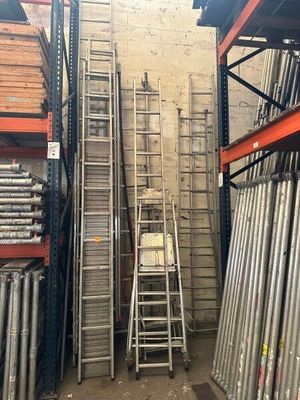 several ladders are stacked up in a warehouse with a ladder leaning against the wall