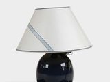 une image représentant une lampe bleue surmontée d'un abat-jour blanc