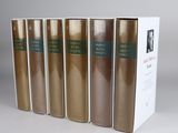 five books in a row in a white box on a table
