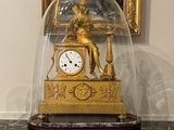 une horloge en or sous un dôme de verre, posée sur une table en marbre