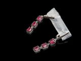 un gros plan sur une paire de boucles d'oreilles en saphir rose sur fond noir