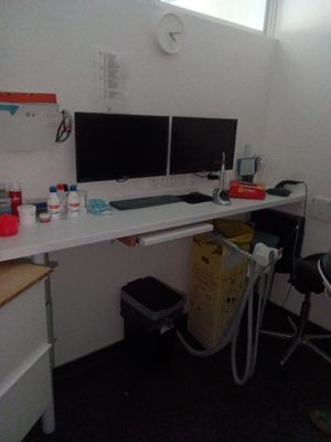 un bureau avec deux écrans et une chaise dans un coin
