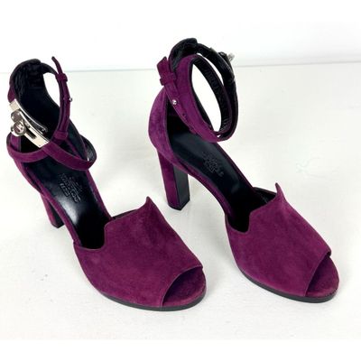 une paire de sandales à talons hauts violettes, ornées d'une boucle métallique à la cheville
