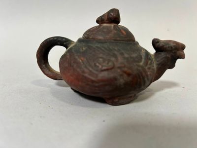 une petite théière marron surmontée d'un oiseau