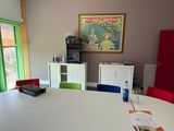 brightly colored chairs around a white table in a room with a painting on the wall