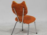 an orange chair with two legs and a cat head on it