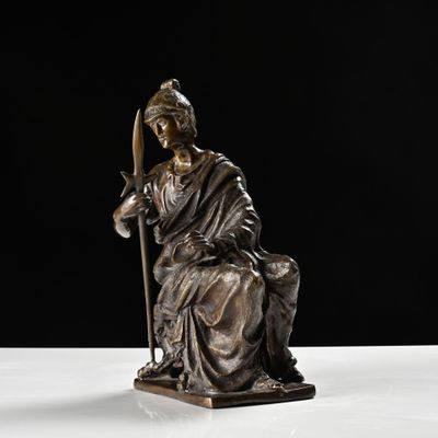 statue d'une femme tenant un bâton, posée sur une surface blanche