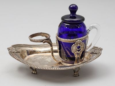 plateau en argent sur lequel sont posés une bouteille en verre bleue et une cuillère