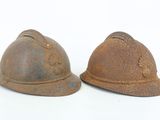 two old helmets sitting next to each other on a white surface