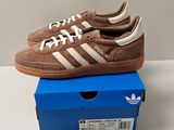 des baskets Adidas marron et blanches posées sur une boîte bleue