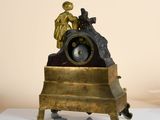 a bronze statue of a man sitting on top of a clock