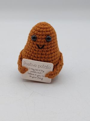 une petite peluche qui tient une pancarte