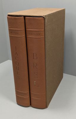 two brown books sitting on top of a table next to each other