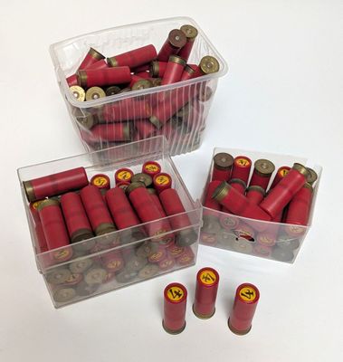 trois récipients en plastique remplis de cartouches de fusil rouges, posés sur une table blanche