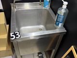 a stainless steel sink in the corner of a bathroom