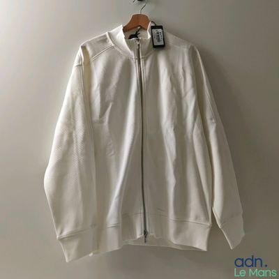 the white jacket is hanging on a hanger on the wall