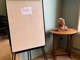 a white board with a sign on it next to a small table with a teddy bear on it