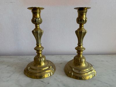 deux chandeliers en or posés sur une table en marbre