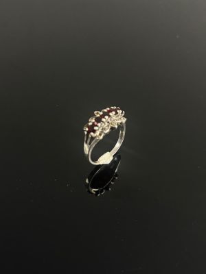 une bague en or blanc sertie de grenats et de diamants sur un fond noir