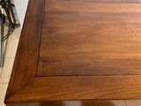 a wooden table with a square top on a tiled floor