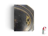 a picture of a black and gold plate on a white background