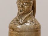 a small vase that has a statue of a man on it