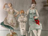 three figurines of women sitting on top of a glass shelf