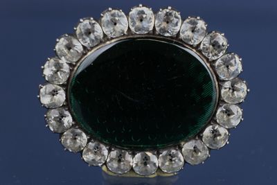 une image représentant une broche verte et blanche entourée de diamants