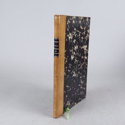 un vieux livre posé sur une table à côté d'un mur blanc